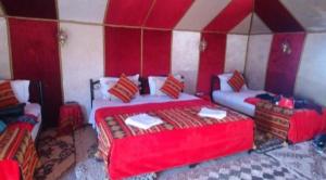 a bedroom with two beds in a red and white room at Merzouga luxurious Camp in Merzouga