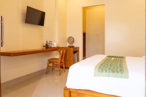 Schlafzimmer mit einem Bett und einem Schreibtisch mit einem TV in der Unterkunft tiny's house in Ubud
