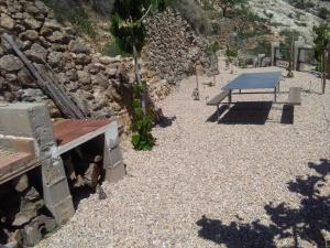 una mesa de picnic en un suelo de grava con una pared de piedra en Casa rural El Cestero, en Castellote