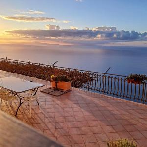 un patio con mesa, sillas y el océano en LA CASA DEL CAPITANO furore amalfi coast, en Furore