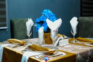een tafel met een geel tafelkleed, glazen en blauwe bloemen bij JEVENOM HOTEL in Ibafo