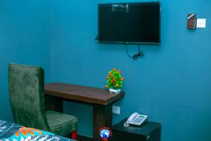 een kamer met een bureau met een stoel en een televisie bij JEVENOM HOTEL in Ibafo