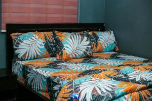 een bed met een kleurrijk dekbed met tropische bladeren bij JEVENOM HOTEL in Ibafo