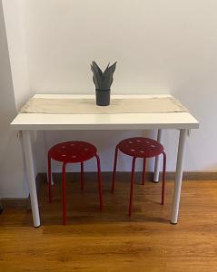 ein weißer Tisch mit zwei roten Hockern und einer Pflanze in der Unterkunft DMT Apartament regim hotelier Rin in Bukarest