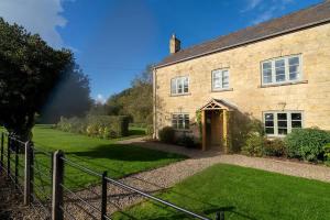 an old stone house with a fence in front of it at Pass the Keys - Cotswolds Farmhouse - Sleeps 10 - Stunning garden in Moreton in Marsh