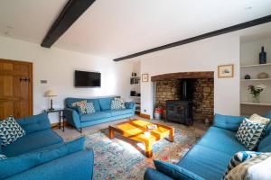 a living room with blue couches and a fireplace at Pass the Keys - Cotswolds Farmhouse - Sleeps 10 - Stunning garden in Moreton in Marsh