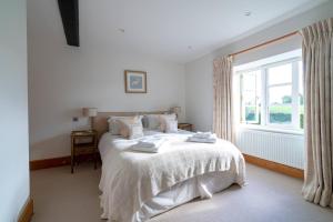 1 dormitorio con 1 cama blanca y ventana en Pass the Keys - Cotswolds Farmhouse - Sleeps 10 - Stunning garden en Moreton in Marsh