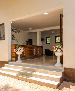 a lobby with two white vases with flowers in them at Hotel Chenra in Kataragama