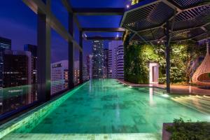 a pool on the roof of a building with a city skyline at Hotel Indigo Kuala Lumpur on the Park, an IHG Hotel in Kuala Lumpur