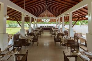 Hotel Chenra في كاتاراغاما: غرفة طعام بها طاولات وكراسي وثريا