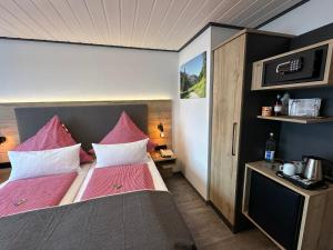 um quarto com uma cama grande e lençóis cor-de-rosa em Ferienhotel Silberdistel garni em Bolsterlang