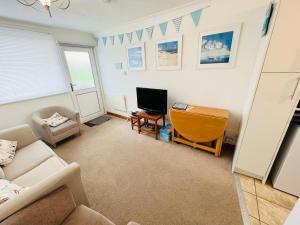 a living room with a couch and a television at 2 Bedroom Chalet SB11, Sandown Bay, Dog Friendly in Sandown
