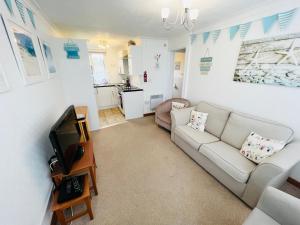 a living room with a couch and a tv at 2 Bedroom Chalet SB11, Sandown Bay, Dog Friendly in Sandown