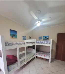 two white bunk beds in a room with a ceiling fan at Apto no Ed. Alexandra I in Guarujá