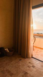 um quarto com uma janela com vista para o oceano em L'Oued the lodge em Imsouane