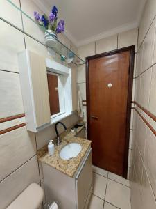 a bathroom with a sink and a wooden door at Quando cama Solteiro in Sorocaba