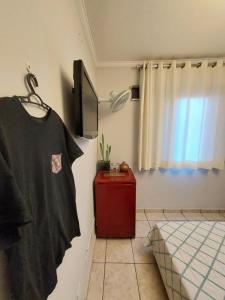 a room with a bed and a t shirt hanging on a wall at Quando cama Solteiro in Sorocaba