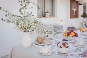a table with a vase of flowers and food on it at La Buena Sombra in Alicante