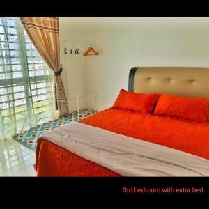 1 dormitorio con cama de color naranja y ventana en Damai Homestay Alor Setar en Alor Setar