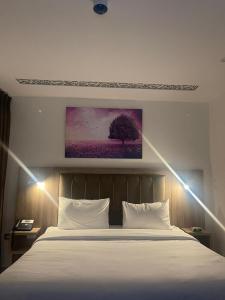 a bedroom with a white bed and a painting on the wall at Antalya Hotel Amman in Amman