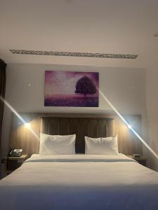 a bedroom with a white bed with a painting on the wall at Antalya Hotel Amman in Amman