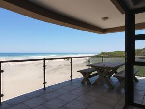 a balcony with a picnic table and the beach at Paradise Beachfront Apartment in Jeffreys Bay
