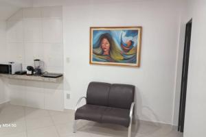 Apartamento top central في Pau dos Ferros: كرسي في غرفة مع لوحة على الحائط