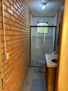 a bathroom with a toilet and a brick wall at Recanto Nativos in Garopaba