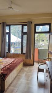a bedroom with a bed and a large window at त्रिnity homestay in Kasol