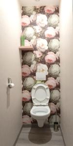 a toilet in a bathroom with a wall covered in flowers at Le Relais de la Poste in Gourdon