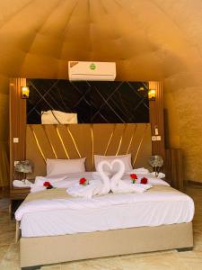 a bed with white sheets and red flowers on it at sand magic camp in Wadi Rum