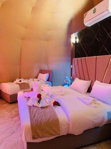 2 camas en una habitación con iluminación púrpura en sand magic camp, en Wadi Rum