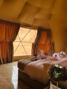 a bedroom with a bed and a large window at sand magic camp in Wadi Rum
