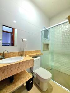 a bathroom with a sink and a toilet and a glass shower at Apartamento com piscina em UBATUBA in Ubatuba