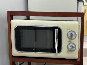 a beige microwave sitting on a wooden stand at Our secret movie theater, Netflix, popcorn, free parking in Seoul