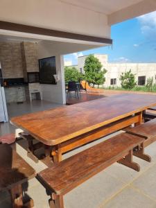 einen großen Holztisch mit Bänken auf einer Terrasse in der Unterkunft Chácara Lótus in Trindade