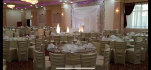 um salão de banquetes com mesas e cadeiras brancas em Nile jewel hotel beni suef em Beni Suef