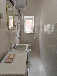 bagno con lavandino, servizi igienici e specchio di Casa in Centro a Fondi