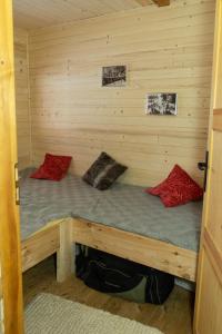 a bed in a log cabin with two red pillows at Drewniany domek pod masywem Śnieżnika in Nowa Morawa