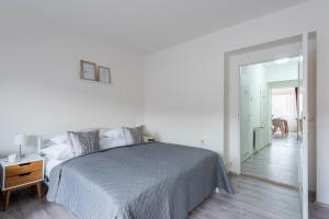 a white bedroom with a bed and a mirror at Prague - Karlin Apartments in Prague