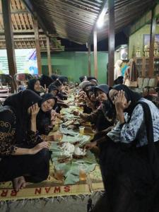 een groep mensen die aan een lange tafel zitten bij Pendopo Kayuwanan Homestay Syariah in Yogyakarta