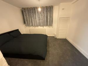 - une chambre avec un lit noir et une fenêtre dans l'établissement Spacious 2 bed Dulwich flat green views, à Londres