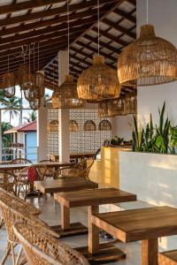 a restaurant with wooden tables and chairs and chandeliers at Lucky's Surf Camp in Weligama