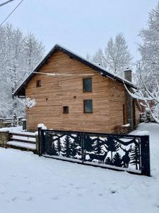 a wooden house with a gate in the snow at Villa Alpina Brezovice in Brezovicë