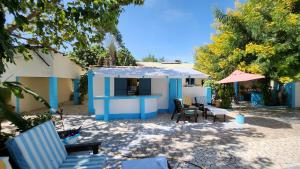 Casa azul y blanca con sillas y mesa en Mango Lodge Gambia, en Brufut