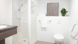 La salle de bains blanche est pourvue d'une douche et de toilettes. dans l'établissement Zenao Appart'Hotel, à Yzeure