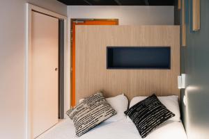 a bedroom with a bed with two pillows on it at Urban Style LES FLEURINES in Villefranche-de-Rouergue