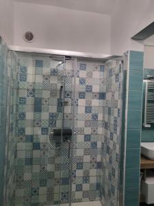 a bathroom with a shower with blue and white tiles at Ma Maison Iris in Turin