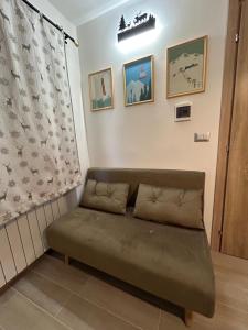 - un canapé vert dans une chambre avec fenêtre dans l'établissement Casa Genziana - nuovo bilocale in centro a Sestriere, à Sestrières