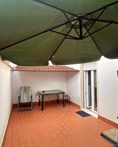 a patio with a table and a chair under a green umbrella at Residenza Mazzini in Avezzano